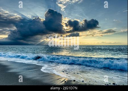 I raggi del sole sono scoppiati attraverso le nuvole in un paesaggio di tramonto dell'oceano Foto Stock