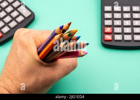 Primo piano di una mano che tiene un mucchio di matite colorate. Foto Stock