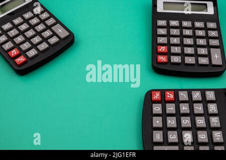 Primo piano di tre calcolatori su una tabella verde. Foto Stock