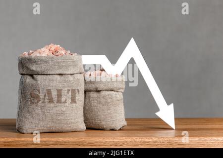 Prezzo del sale. Sacchetto di sale e freccia del grafico rivolta verso l'alto, verso il basso. Carenza di sale ed esportazioni. Foto Stock