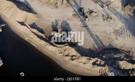 Francia,Parigi-Maggio 26,2022:Scene.Una vista dall'alto dove è possibile vedere grandi camion e trattori che lavorano nella zona montagnosa vicino allo stagno. Alto Foto Stock