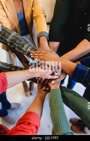Vista ad alto angolo di designer di moda multirazziale accatastamento mani in ufficio Foto Stock