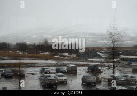 Vetro in un edificio coperto da pioggia, vista di un parcheggio piovoso attraverso la finestra. Foto Stock