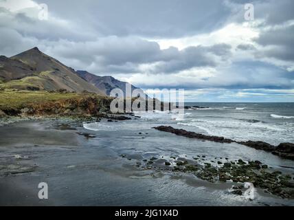 Una spiaggia rocciosa con ormeggio su Islanda in forti venti con surf potente Foto Stock