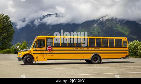 Scuola bus sul parcheggio su sfondo soleggiato. Bus scuola giallo. Foto di strada, nessuno, fuoco selettivo-Giugno 22,2022-Langley BC Canada Foto Stock