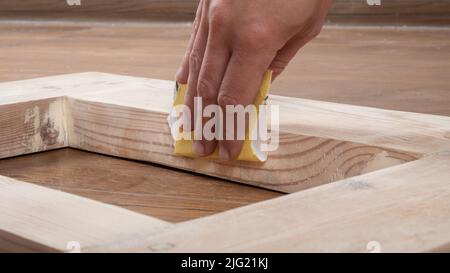 levigatura manuale di porte in legno con carta vetrata. Foto Stock