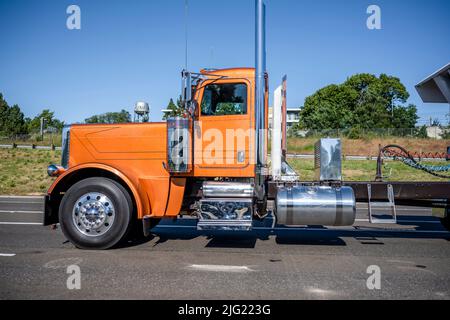 Profilo della cabina basso per migliorare l'aerodinamica trattore semi-camion arancione classico con carro di grandi dimensioni con accessori cromati e tubi di scarico alti per il trasporto del carico i. Foto Stock
