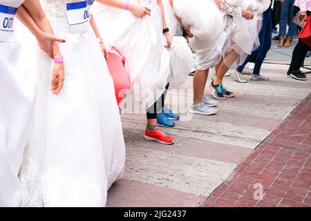 La folla di spose si prepara per la loro corsa allineandosi davanti alla linea di partenza, in cui lo sposo servirà come loro obiettivo. È un inizio di storia di amore. Foto Stock