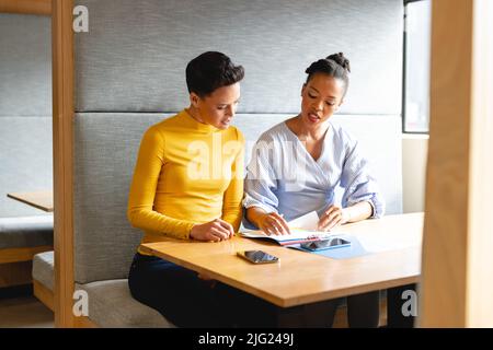 Donne d'affari multirazziali discutere oltre documento in ufficio creativo Foto Stock