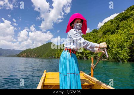 LIJIANG, CINA - 7 LUGLIO 2022 - una bambina di Mosuo pagaie sulla superficie del lago di Lugu a Lijiang, provincia di Yunnan, Cina, 7 luglio 2022. Lago Lugu, conosciuto come Foto Stock