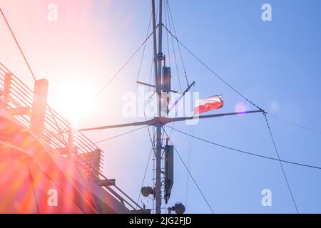 Bandiera della Polonia che sventola sul palo di bandiera della nave. Bandiera polacca che sbatte mentre navighi in barca sul mare. Giorno di sole Foto Stock