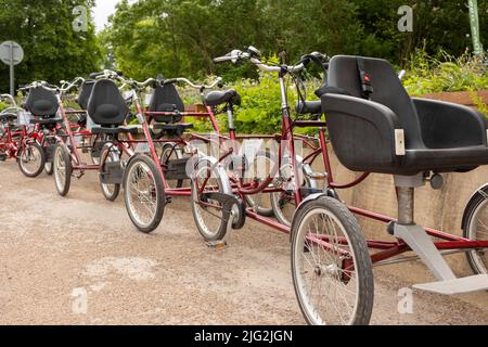 Tunstall , Stoke on Trent regno unito Maggio 27 2022 bicicletta a tandem turistica a due posti rossa a quattro ruote parcheggiata in fila in attesa di essere noleggiata Foto Stock