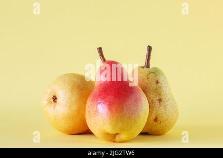 Tre pere mature su sfondo giallo. Foto Stock