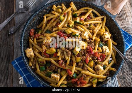 Pasta greca con macaroni, manzo macinato, verdure e formaggio feta in padella Foto Stock