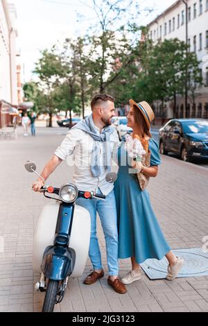 Felice coppia giovane a cavallo di uno scooter in città in una giornata di sole Foto Stock