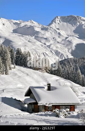 Piccola casa di montagna in legno all'interno di uno scenario innevato montagna, Svizzera, Arosa Foto Stock