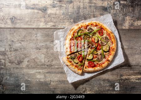 Pizza vegetariana con zucchine, pomodoro, peperoni e funghi su tavola di legno Foto Stock