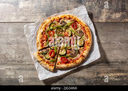 Pizza vegetariana con zucchine, pomodoro, peperoni e funghi su tavola di legno Foto Stock