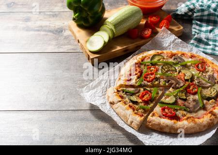 Pizza vegetariana con zucchine, pomodoro, peperoni e funghi su tavola di legno Foto Stock