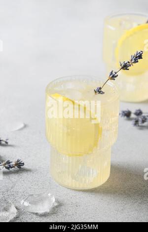 Limonata di lavanda estiva frizzante in bicchieri su sfondo grigio. Formato verticale. Primo piano. Foto Stock