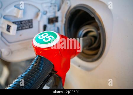 Pompa a lancia rossa benzina Gun dalla pompa dell'olio nel serbatoio dell'auto al rifornimento. Foto Stock