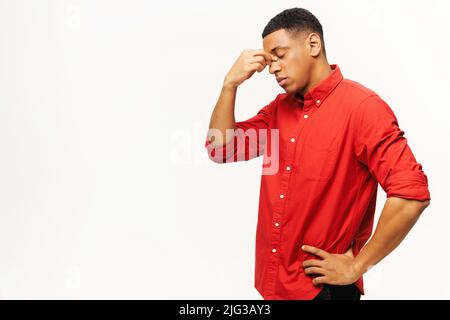 Problema, depressione o malattia. Ritratto di solo triste bel giovane uomo in camicia in piedi, tenendo la testa giù e piangendo. Studio interno girato isolato su sfondo bianco Foto Stock