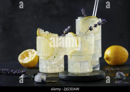 Limonata fredda di lavanda con limone in bicchieri su sfondo nero. Bevande estive per feste di freschezza. Foto Stock