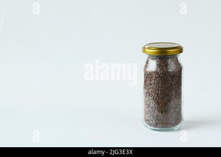 semi di lino in un vaso di vetro su sfondo bianco Foto Stock