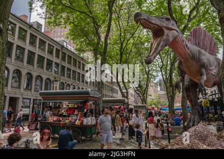 Boston, ma, US-Giugno 11, 2022: Persone al mercato alimentare e destinazione turistica del centro con grande statua di dinosauro sullo sfondo. Foto Stock