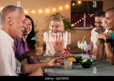 Persone mature di mezza età che hanno cocktail party insieme. Gruppo di amici che allietano i bicchieri da drink che celebrano l'happy hour al bar ristorante. Vecchio Foto Stock