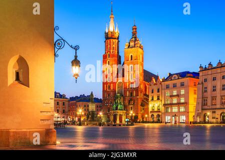 Cracovia, Polonia. Chiesa di Bazylika Mariacka e Sala dei tessuti sulla piazza principale di Cracovia, illuminata di notte Foto Stock