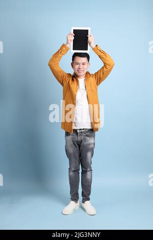 L'uomo asiatico LGBTQ con camicia gialla in piedi su sfondo blu. Foto Stock