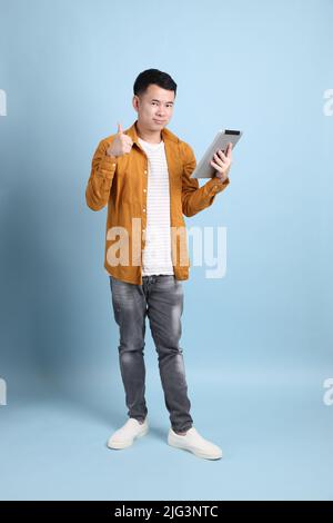L'uomo asiatico LGBTQ con camicia gialla in piedi su sfondo blu. Foto Stock