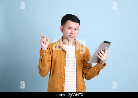 L'uomo asiatico LGBTQ con camicia gialla in piedi su sfondo blu. Foto Stock