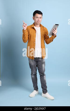 L'uomo asiatico LGBTQ con camicia gialla in piedi su sfondo blu. Foto Stock
