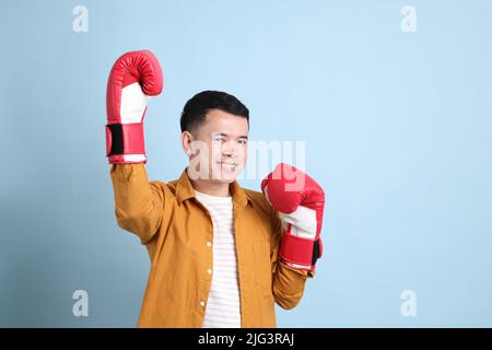 L'uomo asiatico LGBTQ con camicia gialla in piedi su sfondo blu. Foto Stock