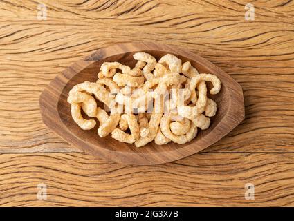 Crackling di pelle di maiale fritto su un piatto su tavola di legno. Foto Stock
