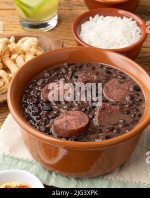 Tipica feijoada brasiliana con riso, caipirinha, farofa e cracklings. Foto Stock