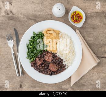 Tipica feijoada brasiliana con riso, pepe, farofa, kale e crackling. Foto Stock