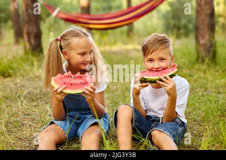 Bambini che mangiano cocomero nel parco. Foto Stock