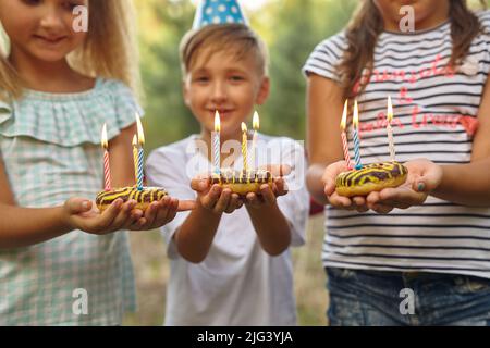 Ragazzo e ragazze festeggiano il compleanno all'aperto in giardino Foto Stock