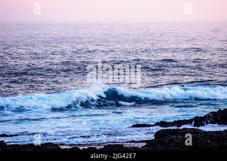 Onde turchesi che si infrangono al crepuscolo lungo la costa Tsitsikamma del Sudafrica Foto Stock