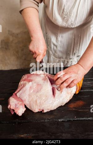 Affettare carne di maiale cruda nel mercato agricolo Foto Stock