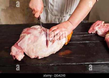 Affettare carne di maiale cruda nel mercato agricolo Foto Stock