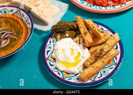 Tradizionale pasto arabo mediterraneo di pane piatto, salsa di lenticchie rosse, dolma e yogurt, guarnito con erbe e olio d'oliva Foto Stock