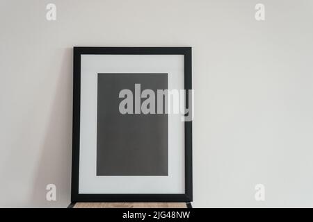 La cornice fotografica in legno bianco si trova all'interno su uno sfondo bianco. Mockup Foto Stock