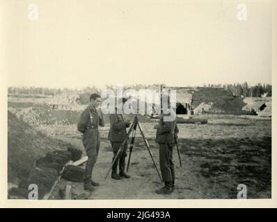 Ritratto di un gruppo divisionale nello spazio in costruzione, uno accanto alla teodolite o strumento di misurazione del terreno. Ritratto di tre divisionali (uno potrebbe essere un ufficiale), sul terreno in costruzione sullo sfondo vi è una casamata in assemblea il carattere centrale scrive i dati raccolti in uno strumento di misura della terra, eventualmente una teodolite, situato su un treppiede riproduzione digitale. Madrid: Red.es: Ministero della Difesa, 2015 Foto Stock
