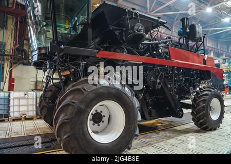 Primo piano della nuova trebbiatrice in fase di produzione. Linea di trasporto per il montaggio e la produzione di mietitrebbia moderne. Macchine industriali. Foto Stock