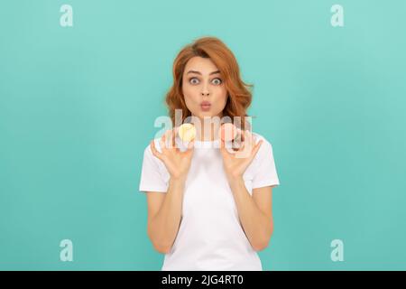 sorpresa ragazza tenere dolce macaron francese cookie su sfondo blu Foto Stock