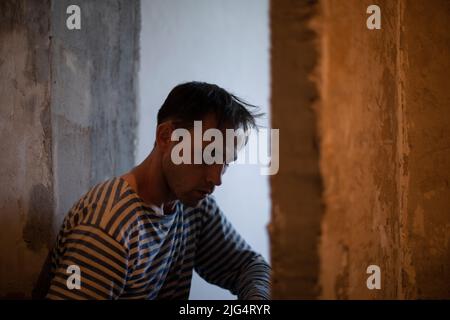 L'uomo sta ristrutturando la casa. Riparazione di pareti in appartamento. La persona lavora. Foto Stock